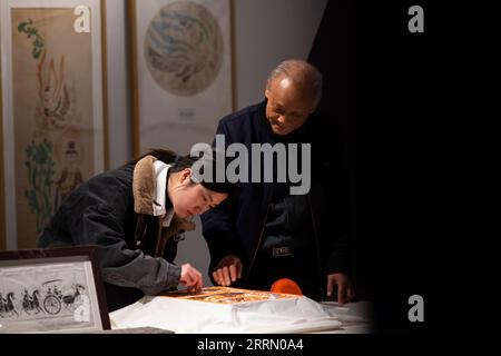221121 -- ZHENGZHOU, Nov. 21, 2022 -- Li Renqing instructs his apprentice to apply ink onto rubbing paper at an exhibition hall of Zhengzhou Shang Dynasty Ruins Museum in Zhengzhou, central China s Henan Province, Nov. 17, 2022. Making rubbings for tablet inscriptions is a craft with a history of over 1,000 years in China, invented as a way to copy documents even before the art of printing. Upgrading the traditional rubbing craft which can only be applied to flat surface, Li Renqing, born in 1963 in Xinyang of central China s Henan Province, has been working for a whole life on rubbings of hig Stock Photo