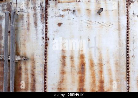 Old rusty storage tank panels with nuts and bolts and wood attached. Copy or text space Stock Photo