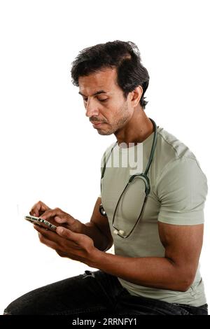 Thirty-something doctor, man, using his smartphone during a pause. Internet shopping, social media. Studio shot on white background. Stock Photo