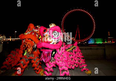 230114 -- LONDON, Jan. 14, 2023 -- Traditional Chinese lion dancers perform in front of the London Eye which is lit up in red to celebrate the upcoming Chinese New Year in London, Britain, Jan. 13, 2023.  BRITAIN-LONDON-LONDON EYE-RED LIGHT LixYing PUBLICATIONxNOTxINxCHN Stock Photo