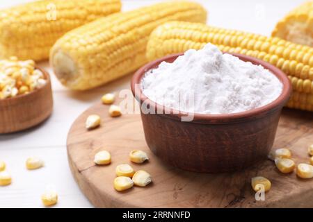 Bowl with corn starch and kernels on white table, closeup Stock Photo