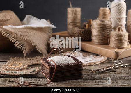 Pieces of burlap fabric, spools of twine and different sewing tools on wooden table Stock Photo