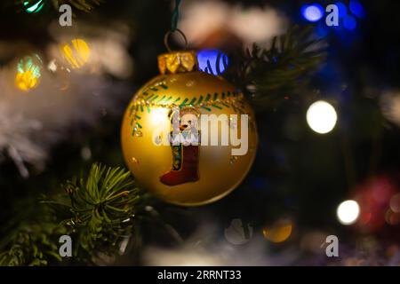 Picture of a teddy bear sitting in a boot painted on a golden Christmas bauble Stock Photo