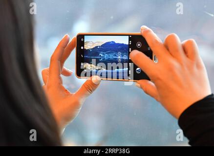 230215 -- GENEVA, Feb. 15, 2023 -- A Chinese tourist takes pictures of the scenery out of the window on the Zentralbahn from Lucerne to Interlaken, Switzerland, Feb. 14, 2023. A group of 25 people from China visited the city of Lucerne and the popular scenic spot and winter sports resort Jungfrau in central Switzerland on Feb. 13-14, after three years of pandemic-related hiatus. I am very excited to see all these again, said Cui Chenghai, a tourist who frequented Switzerland before the outbreak of the pandemic. It has been three years and everything here has no change, but my feeling is differ Stock Photo