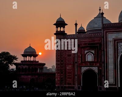 The mosque at the Taj Mahal at sunset is positioned in front of golden red skies that is caused by pollution from burning fields in the Uttar Pradesh Stock Photo