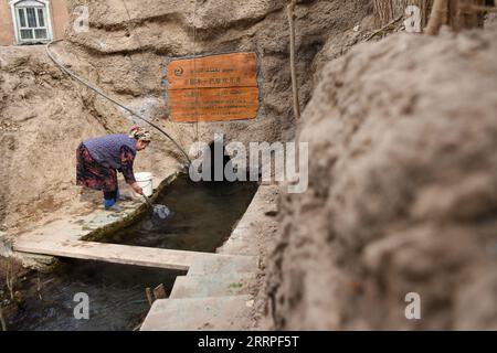 230320 -- URUMQI, March 20, 2023 -- A resident fetches water from the outlet of a karez well in Turpan, northwest China s Xinjiang Uygur Autonomous Region, March 7, 2023. Located at the southern foot of the Tianshan Mountains, Turpan in Xinjiang Uygur Autonomous Region is one of the driest and hottest places in China, with an average annual precipitation of only 16 millimeters and evaporation of up to 3,000 millimeters. In order to make this vast Gobi into a comfortable and livable oasis, the local people found new way as water reserve in karez well, an invention that provides water source fro Stock Photo