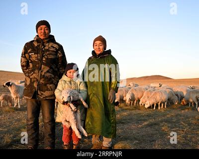 230403 -- XILINGOL LEAGUE, April 3, 2023 -- Herdsman Tsogdelger L poses for a group photo with his wife Munguntuya R and daughter Halgian in the pasture in West Ujimqin Banner of Xilingol League, north China s Inner Mongolia Autonomous Region, March 29, 2023. In spring, the busiest season of the year, Tsogdelger, a herdsman of the Mongolian ethnic group, and his family need to assist with lambing and feed livestock every day. More than 280 lambs have been born in his farm since March 18. From the beginning of this year until March 30, a total of 581,300 offspring were born in West Ujimqin Bann Stock Photo