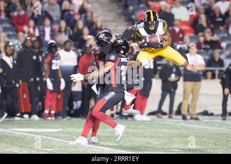 Hamilton Tiger-Cats defensive back Javien Elliott hands the ball