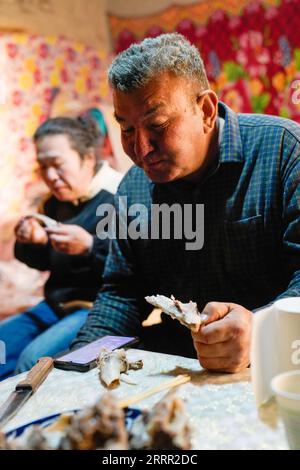 230427 -- YULI, April 27, 2023 -- Arkin Reyim looks for tractors for spring ploughing via his mobile phone as he takes a meal in Yuli County, northwest China s Xinjiang Uygur Autonomous Region, April 1, 2023. Arkin Reyim is a 51-year-old cotton farmer with more than 300 mu 20 hectares of cotton fields in the Bax Mali Village of Yuli County in Xinjiang. Arkin s courage and unique vision has prompted him to start growing cotton in 2004 when he got married with his wife Hasiyat Kasim. Since then, Arkin has devoted himself into the cultivation of cotton for over 10 years, thus making him an experi Stock Photo