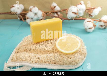 Lemon soap and lemon slice on a loofah bath scrub with cotton buds flowers, side view product photography Stock Photo