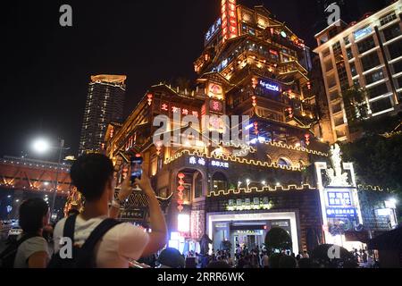 230510 -- BEIJING, May 10, 2023 -- A visitor takes photos in Hongyadong scenic spot at night in Yuzhong District, southwest China s Chongqing Municipality, Sept. 9, 2019. Chongqing, a city built on mountains, features a city scape of ups and downs and scattered buildings. The road is often seen being built on the roof, and the light rail running through the buildings in the southwest China s metropolitan. With the natural advantages for parkour, also known as free-running, Chongqing provides the practitioners of parkour a playground where they overcome obstacles in the urban landscape without Stock Photo