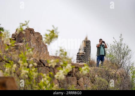 230514 -- ZUNHUA, May 14, 2023 -- Zhao Chunsheng looks out on the Great Wall in Zunhua City, north China s Hebei Province, May 13, 2023. Zhao Chunsheng, 52, is a villager from Qianhouzhangzi Village, Houjiazhai Township of Zunhua City. In 2018, he was hired by local cultural protection department as a Great Wall protector. Zhao is responsible for guarding about five kilometers of the Great Wall built in Ming dynasty 1368-1644, including five watch towers and four beacon towers. Every two or three days, he would patrol the Great Wall, clear rubbish and weeds, and arrange fallen bricks. The job Stock Photo