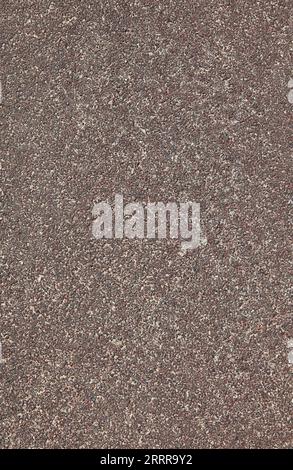 Red rubber floor, texture, background. Dusty and worn backdrop. Faded, old, granular rubber coating. Surface with blurry sand-filled chaotic pattern Stock Photo