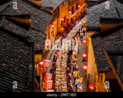 230621 -- NINGGUO, June 21, 2023 -- This aerial photo taken on June 16, 2023 shows a lantern performance by the long-table banquet in Hule Town of Ningguo City, east China s Anhui Province. Hule Town, an ancient town in east China s Anhui Province, has a tradition of lantern performance to celebrate festivals. As the Dragon Boat Festival approaches, villagers perform lantern dance with lanterns in the shape of fish and dragon, and place lotus-shaped water lanterns in the river. A series of activities including the long-table banquet and the lantern fair have been held to attract tourists from Stock Photo
