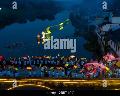 230621 -- NINGGUO, June 21, 2023 -- This aerial photo taken on June 16, 2023 shows a lantern performance in Hule Town of Ningguo City, east China s Anhui Province. Hule Town, an ancient town in east China s Anhui Province, has a tradition of lantern performance to celebrate festivals. As the Dragon Boat Festival approaches, villagers perform lantern dance with lanterns in the shape of fish and dragon, and place lotus-shaped water lanterns in the river. A series of activities including the long-table banquet and the lantern fair have been held to attract tourists from home and abroad. Photo by Stock Photo