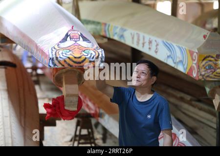 230624 -- FUZHOU, June 24, 2023 -- Fang Shaohuang, an inheritor of the city-level intangible cultural heritage of dragon boat making techniques, checks a newly built dragon boat, which will be presented to the rowers from Matsu as a gift, in Minhou of southeast China s Fujian Province, on May 23, 2023. The Dragon Boat Festival, also known as Duanwu Festival, traditionally falls on the fifth day of the fifth month in the Chinese lunar calendar. The dragon boat competition, a traditional part of the festival, has gained popularity on both sides of the Taiwan Strait, bringing excitement to a wide Stock Photo