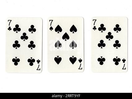 Vintage playing cards showing three sevens on a white background. Stock Photo