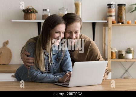 Happy positive millennial husband and wife using online application Stock Photo