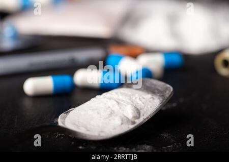 Set of drugs in powder and tablets on a black background. Heroin in a spoon Stock Photo
