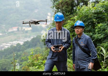 230812 -- PINGXIANG, Aug. 12, 2023 -- Li Yingxing L and Yao Zhengqiang operate a drone to inspect power transmission lines and equipment in Pingxiang, south China s Guangxi Zhuang Autonomous Region, Aug. 10, 2023. Wen Xianwen, Yao Zhengqiang, Deng Yiqiang and Li Yingxing are members of a team of maintenance personnel from the Guangxi branch of China Southern Power Grid s Pingxiang power supply station. Workers of the team, which was founded in 1974, have patrolled nearly 250,000-kilometer-long power transmission lines over the past 49 years. Led by Wen at present, the team has entered its four Stock Photo