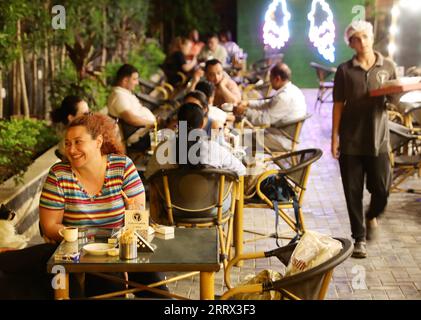 230818 -- BEIJING, Aug. 18, 2023 -- People sit and chat at a cafe in Cairo, Egypt, July 23, 2023. Chongqing, a city by the Yangtze River, is called stove by Chinese people because of its high temperature in summer Cairo, located on the bank of the Nile, has long been a hot place on the edge of desert. Both cities have been vigorously promoting the night economy. Hongyadong in Chongqing is an ancient city gate that has been transformed into a giant suspended building featuring restaurants and other entertainment venues. Khan el-Khalili in Cairo, the centuries-old marketplace, is considered one Stock Photo