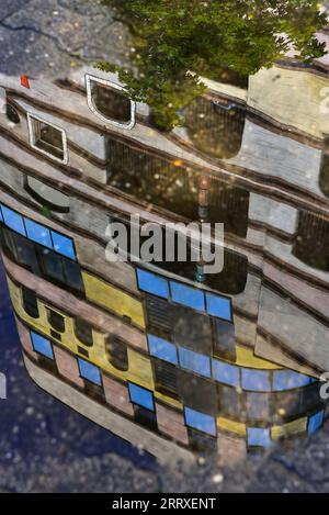 The 'Waldspirale' (forest spiral) residential complex completed in 2000 in Darmstadt, Germany, mirrored in a water puddle Stock Photo