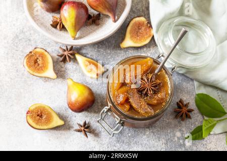 Homemade fig sweet jam in a glass jar with fresh figs on a light gray table. Autumn harvest preservation, healthy fermented food. Stock Photo