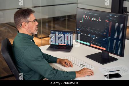 Busy mature business investor stock trader analyzing investing trading market. Stock Photo