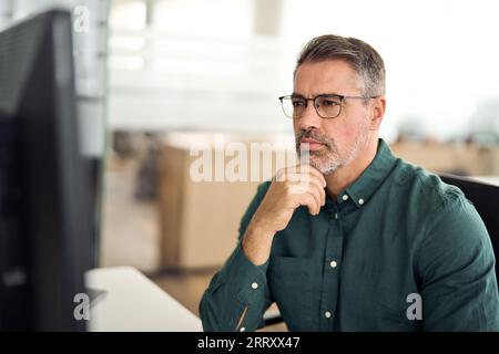 Serious busy mature business man looking at computer working in office. Stock Photo