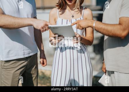 Aesthetic architects discussing blueprint outdoors, collaborating on a modern building design, focusing on successful teamwork and urban structure. Pa Stock Photo