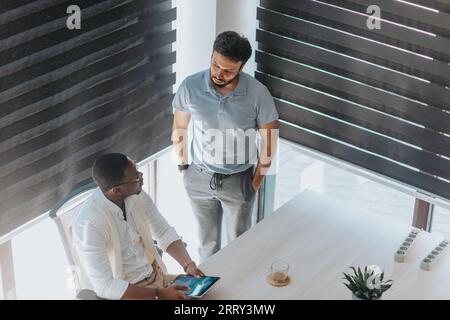 Diverse business colleagues collaborating, using technology, discussing projects, and aiming for success. Stock Photo