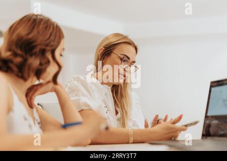 Businesswomen analyze data, collaborate, and work in an office to develop profitable business strategies with technology. Stock Photo