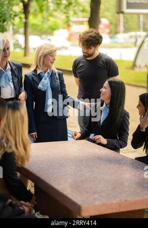 Classmates discussing school project after classes gathered at table in the university yard. Stock Photo