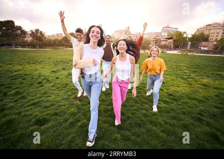 Multiracial youth group having fun and running around green meadow. Outdoor recreational activities Stock Photo
