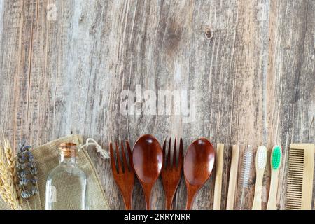 Eco-friendly spoons, forks, bamboo straws, toothbrushes, hair comb, glass container, and reusable bag on wooden table. Sustainable lifestyle concept. Stock Photo