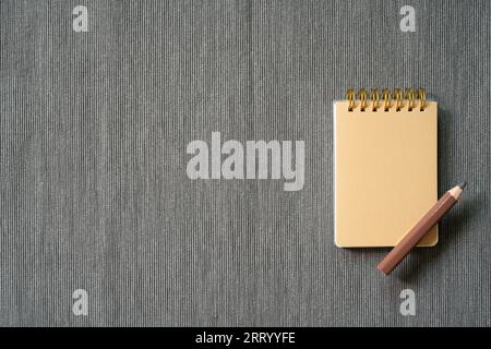 Brown notepad and colored pencil on gray fabric background. top view, copy space Stock Photo
