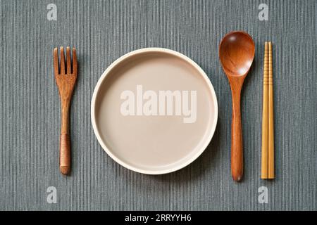 Kitchenware. dish, wooden spoon, fork, chopsticks on gray fabric background. top view, copy space Stock Photo