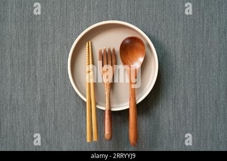 Kitchenware. dish, wooden spoon, fork, chopsticks on gray fabric background. top view, copy space Stock Photo