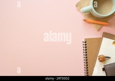 Notebook, clipboard, pouch, colored pencil, cup of coffee, dry flower on pink desk background. flat lay, top view, copy space. workspace Stock Photo