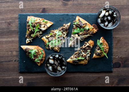 Slices of mushroom and beef flatbread pizza topped with arugula Stock ...