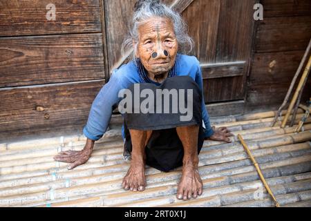 Portrait of elderly Indian Apatani ethnic minority tribal woman with black wooden nose plugs and traditional face tattoos, Arunachal Pradesh, India Stock Photo