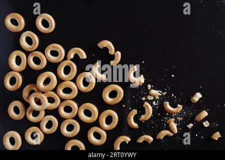 Small dry bagels whole and broken on old black metal background, top view Stock Photo