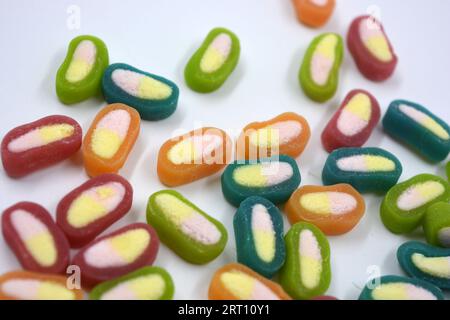 Interesting and unusual, colored caramel candies, sweets with a white center are located on a white matte background. Stock Photo