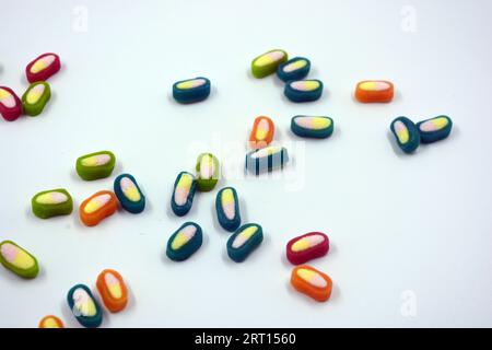 Interesting and unusual, colored caramel candies, sweets with a white center are located on a white matte background. Stock Photo