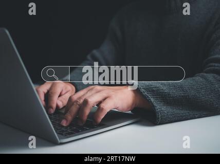 Human hand working on computer and search icon. The concept of searching for information from the internet network. Stock Photo