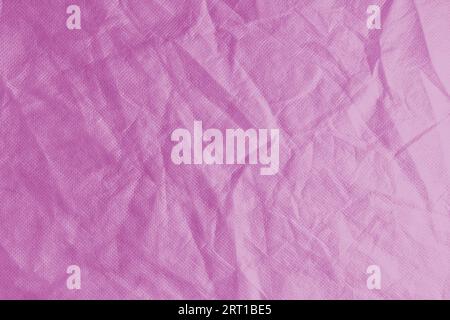 Wrinkled, crumpled pink fabric texture background. Wrinkled and creased abstract backdrop of spunbond  textile, wallpaper with copy space, top view. Stock Photo