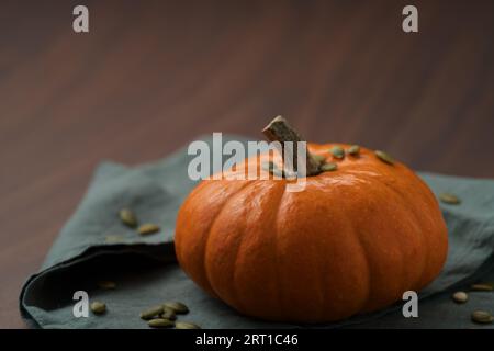 Orange pumpkin on linen napkin on wood table for seasonal background, shallow focus Stock Photo