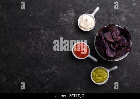 Purple sweet potato chips with sauces, healthy snack on black stone background Stock Photo