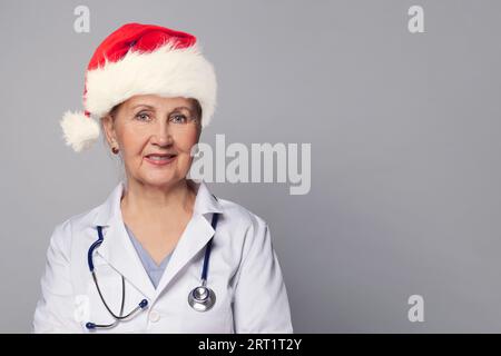 Xmas portrait of Christmas doctor wearing  professional medical  coat, stethoscope and red Santa hat smiling on white Stock Photo