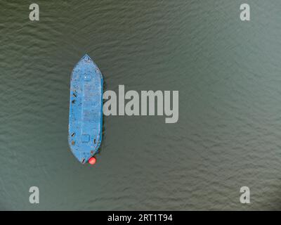 Aerial top down drone shot of blue buoy in the form of a boat used as resting or relaxing place for swimmers in lake of local recreation area Stock Photo